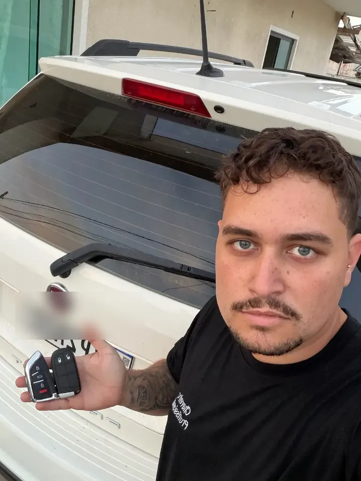 Arthur Colares mostrando duas chaves ao lado de um carro branco