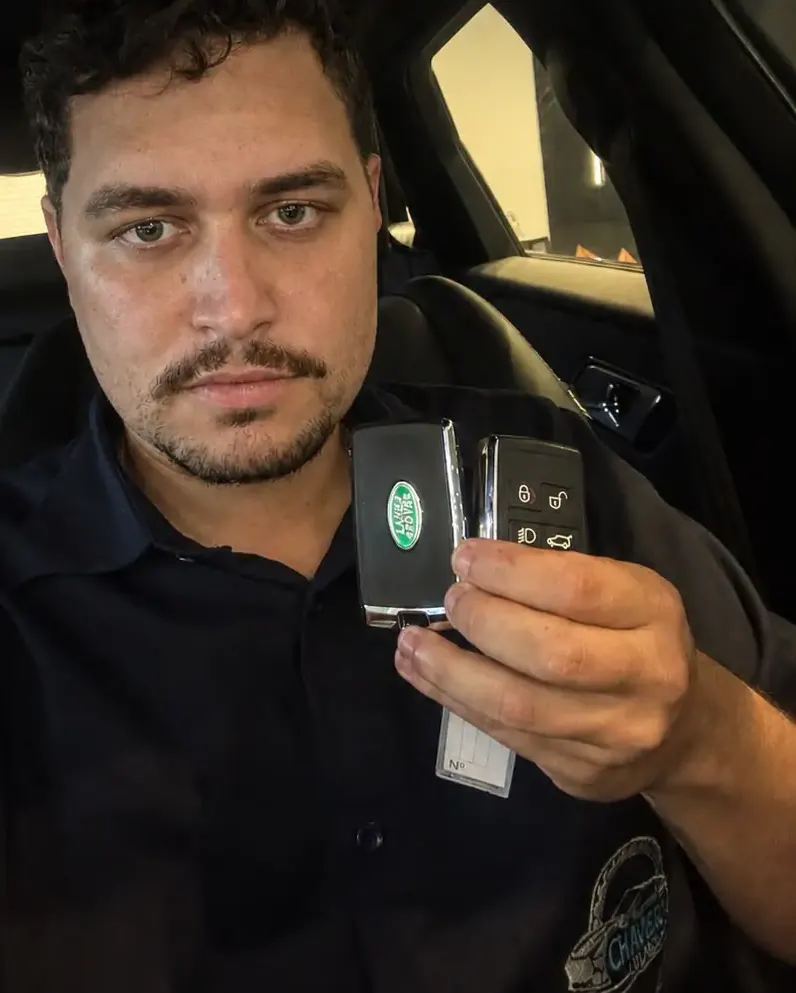 Arthur Colares, técnico do Chaveiro Colares, segurando duas chaves presenciais Land Rover