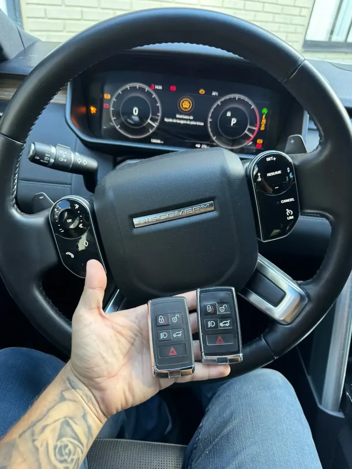 Duas chaves presenciais Land Rover em frente ao volante de um Land Rover Discovery