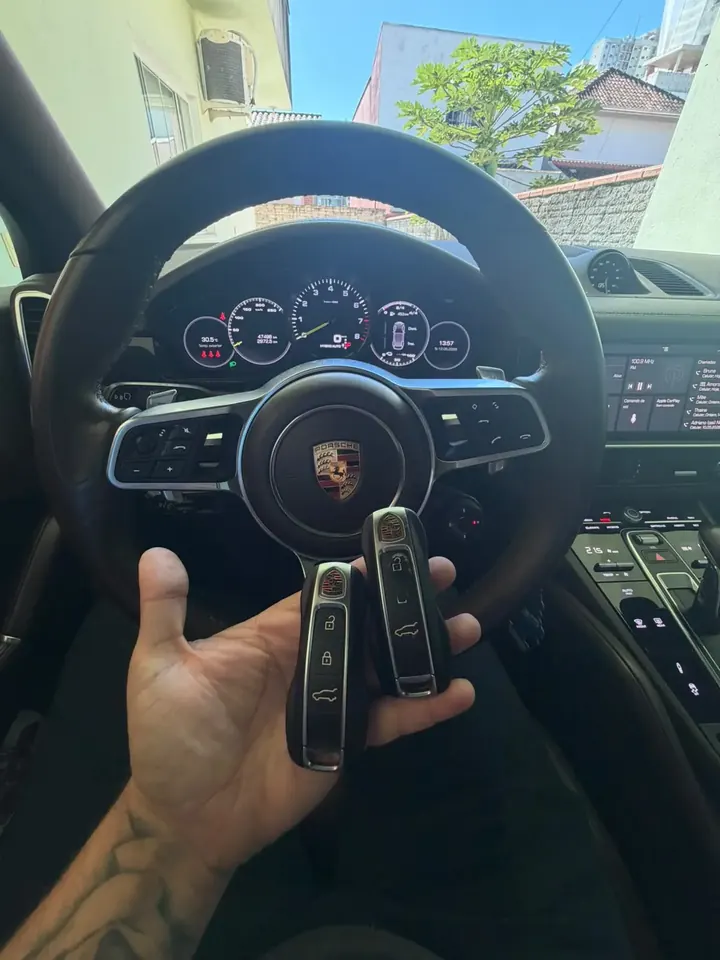 Par de chaves presenciais Porsche em frente ao volante de um Porsche Cayenne